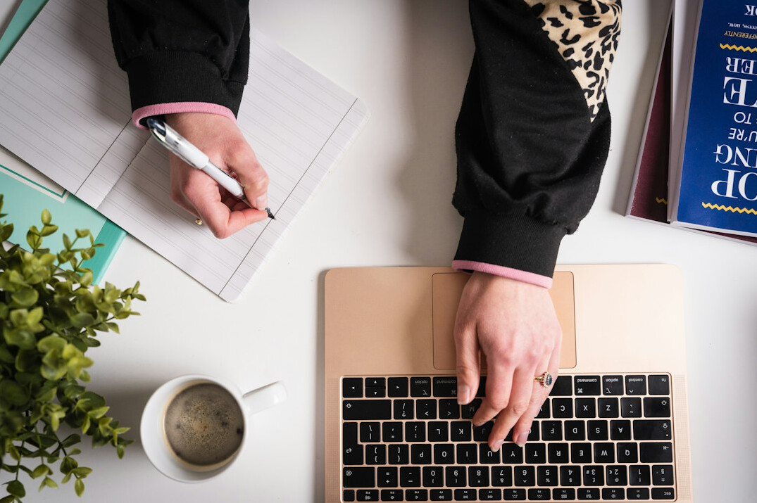 person writing code on laptop at desk